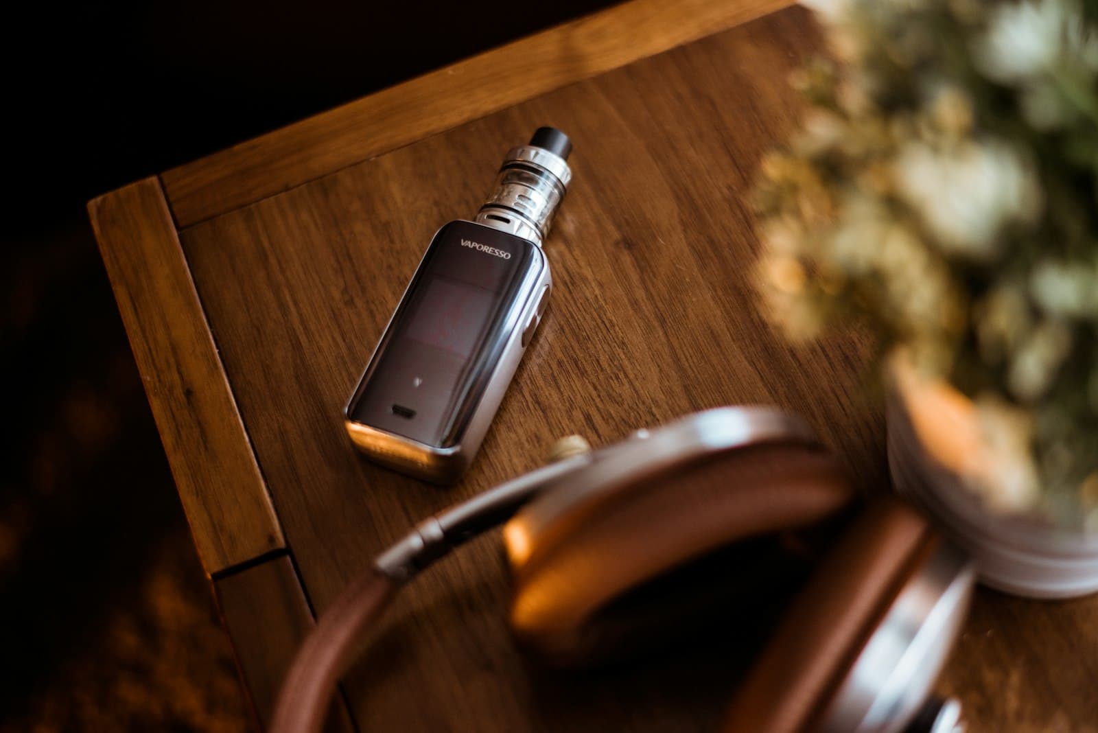A small black pod vape kit resting on a wooden table